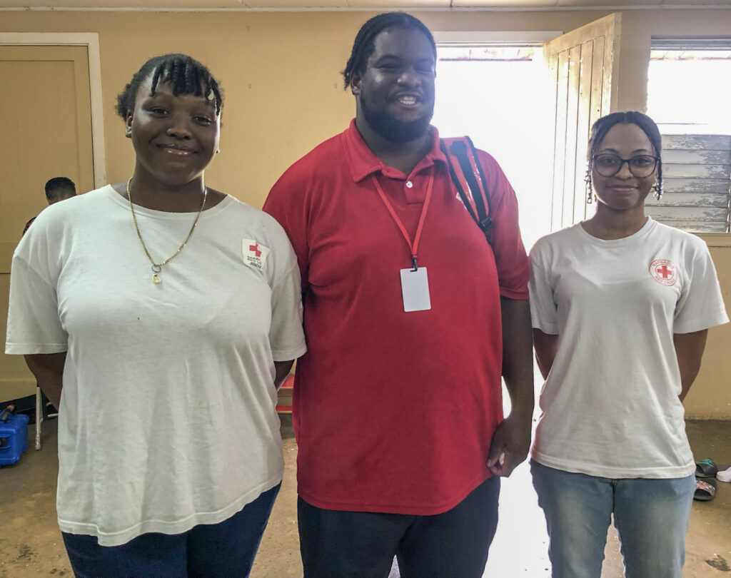 Image of a woman in a white shirt, a man in a red shirt, and another woman in a white shirt posing together for the camera.