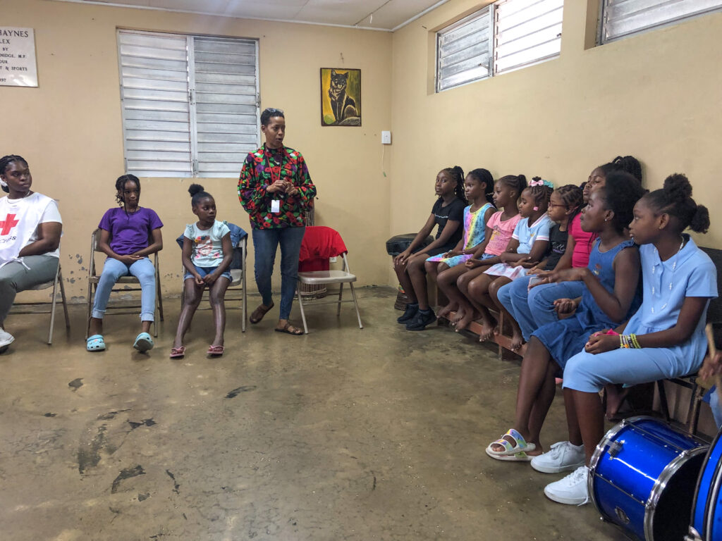 Image of a woman surrounded by children who all listen attentively to her.