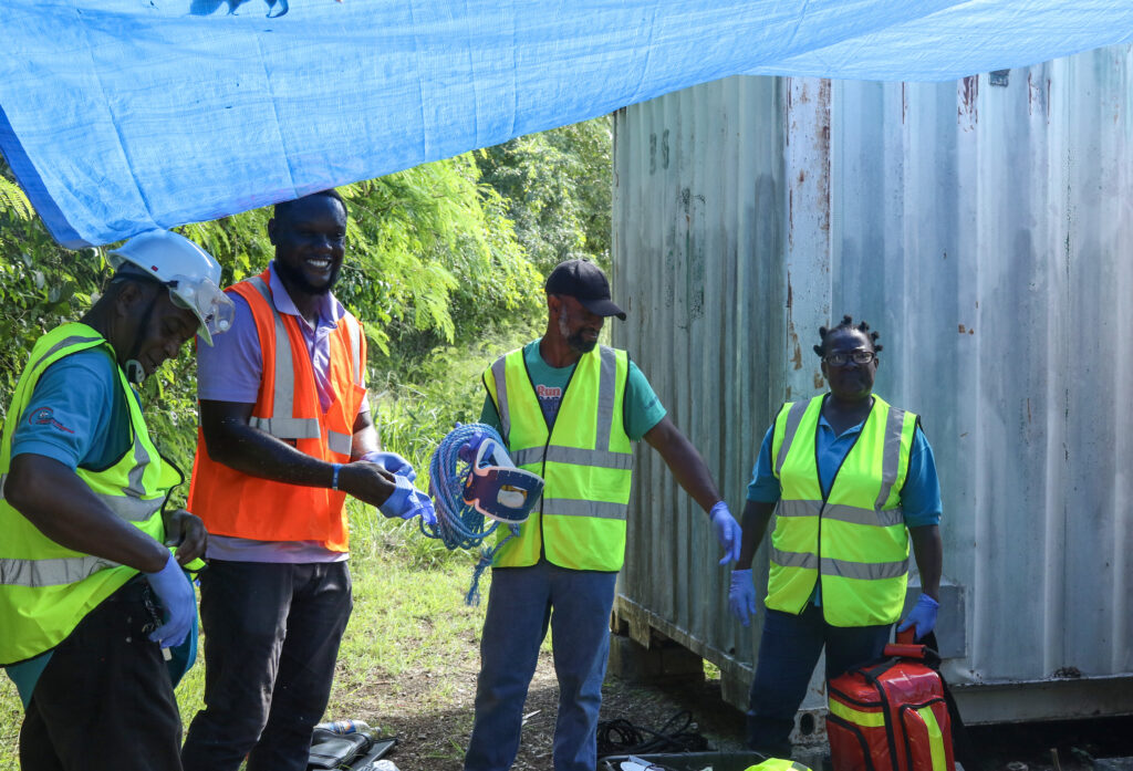 Image of four people, three in neon yellow vests and one in an orange vest, standing outside as they train for becoming a community disaster response team.