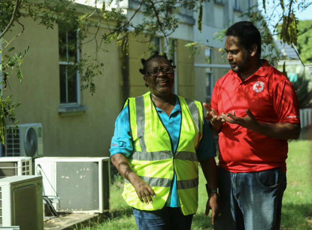 Image of a woman in a neon safety vest talking to a man in a red cross shirt as they practice community disaster response team training.